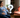 A pregnant woman sitting in a chair next to a red light therapy device with a question mark between them.