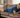 A man lying on a sofa with a blue heating pad on his shoulder, smiling and relaxing.