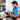 A man in a gym winces in pain while clutching his knee, which is covered by a blue compression wrap.