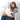 Woman sitting on a sofa reading a book while wearing a blue weighted heating pad around her neck.