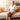 Elderly woman sitting on a sofa wearing a red light therapy knee massager wrap.