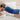 A woman lying face down on a bed with a large blue plush heating pad covering her entire back.
