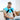 A man sitting on a sofa wearing a blue shoulder ice pack wrap while using a laptop.