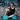 Man in gym using a dual-channel TENS EMS unit with independent intensity for his arm and leg.