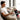 Smiling man on sofa using electric heating pad wrap on leg for pain relief.
