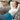 Woman relaxing on a sofa with a blue weighted heating pad on her lap.