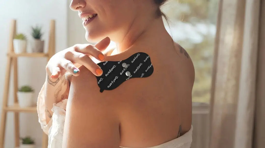 woman applying a black pain relief patch to her shoulder