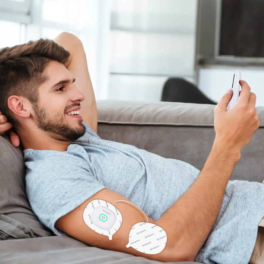 Man using TENS unit on arm while on phone