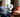 A pregnant woman sitting in a chair next to a red light therapy device with a question mark between them.