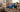 A man lying on a sofa with a blue heating pad on his shoulder, smiling and relaxing.