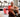 White rectangular red light therapy panel with stand illuminating a seated shirtless older man in a gym with treadmills in