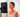 A woman sits with her eyes closed, facing a red light therapy panel for skin treatment.