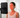 A woman sits with her eyes closed, facing a red light therapy panel for skin treatment.
