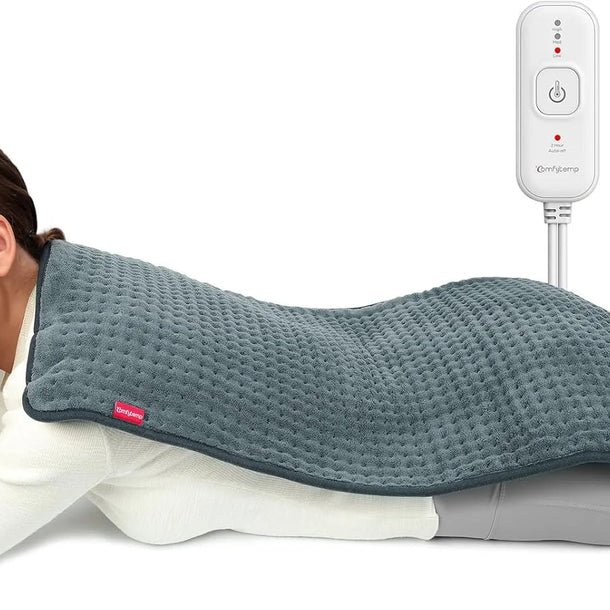 Woman lying down with a Comfytemp weighted heating pad on her back for pain relief.