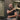Man in a gym holding his shoulder in pain while sitting on a bench.